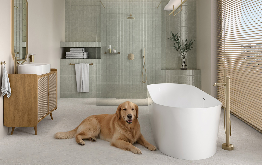 Golden retriever leżący na brudnej podłodze w łazience z białymi płytkami, obok białej wolnostojącej wanny i drewnianej szafki z umywalką nablatową.